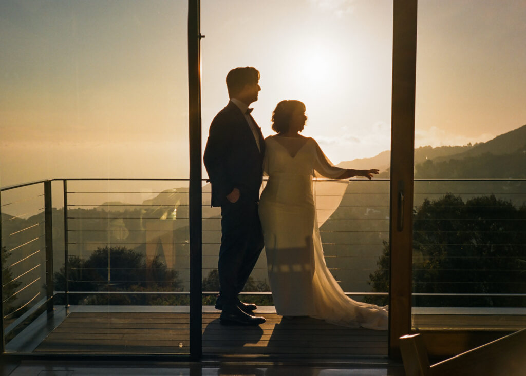 Bride and Groom standing on a balcony overlooking Topanga Canyon during sunset.