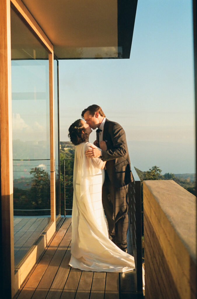 Bride and groom on balcony at the Saddle Peak House in Topanga Canyon during sunset.
