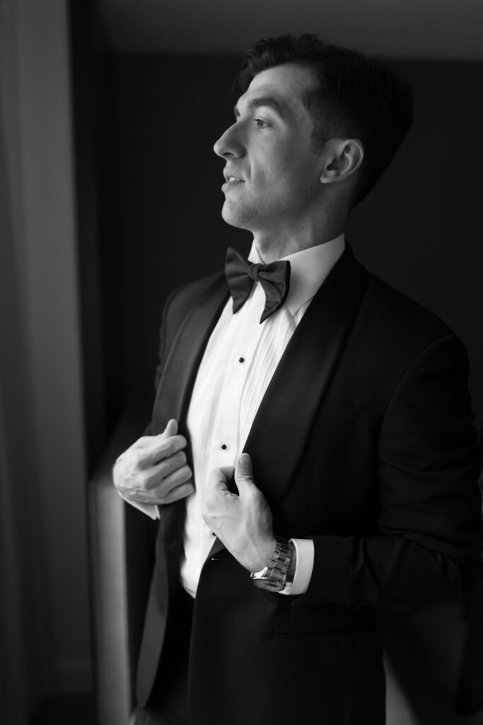 Fine art portrait of the groom putting on his jacket in the groom's getting ready suite at the Hyatt Hotel in Washington DC.