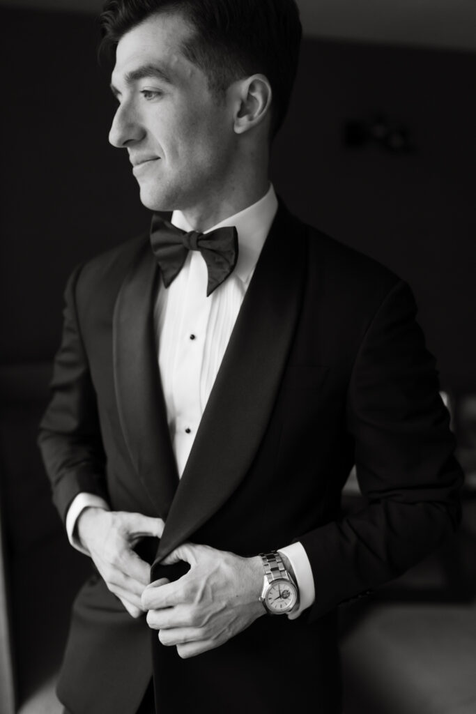 Fine art portrait of the groom putting on his jacket in the groom's getting ready suite at the Hyatt Hotel in Washington DC.