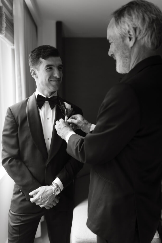 Fine art portrait of the groom's father putting on his boutonniere  in the groom's getting ready suite at the Hyatt Hotel in Washington DC.
