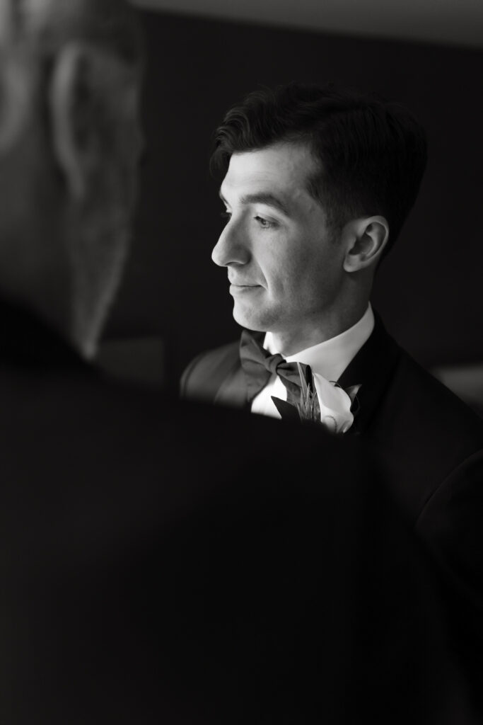 Fine art portrait of the groom's father putting on his boutonniere  in the groom's getting ready suite at the Hyatt Hotel in Washington DC.