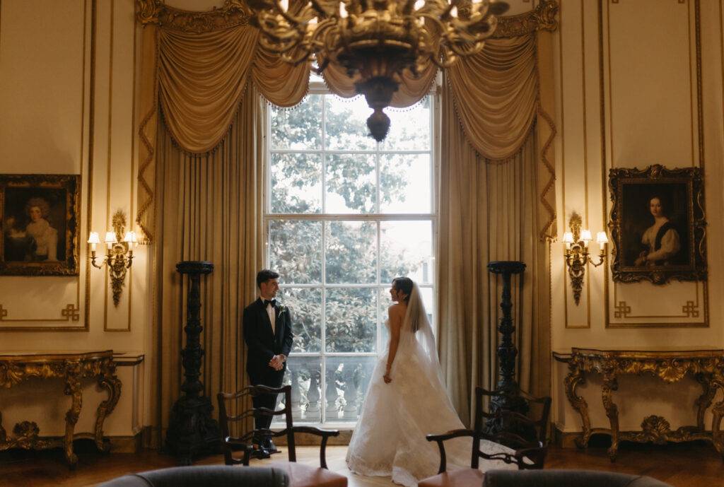 Bride and groom under the chandeliers inside the Larz Anderson House during their black tie wedding