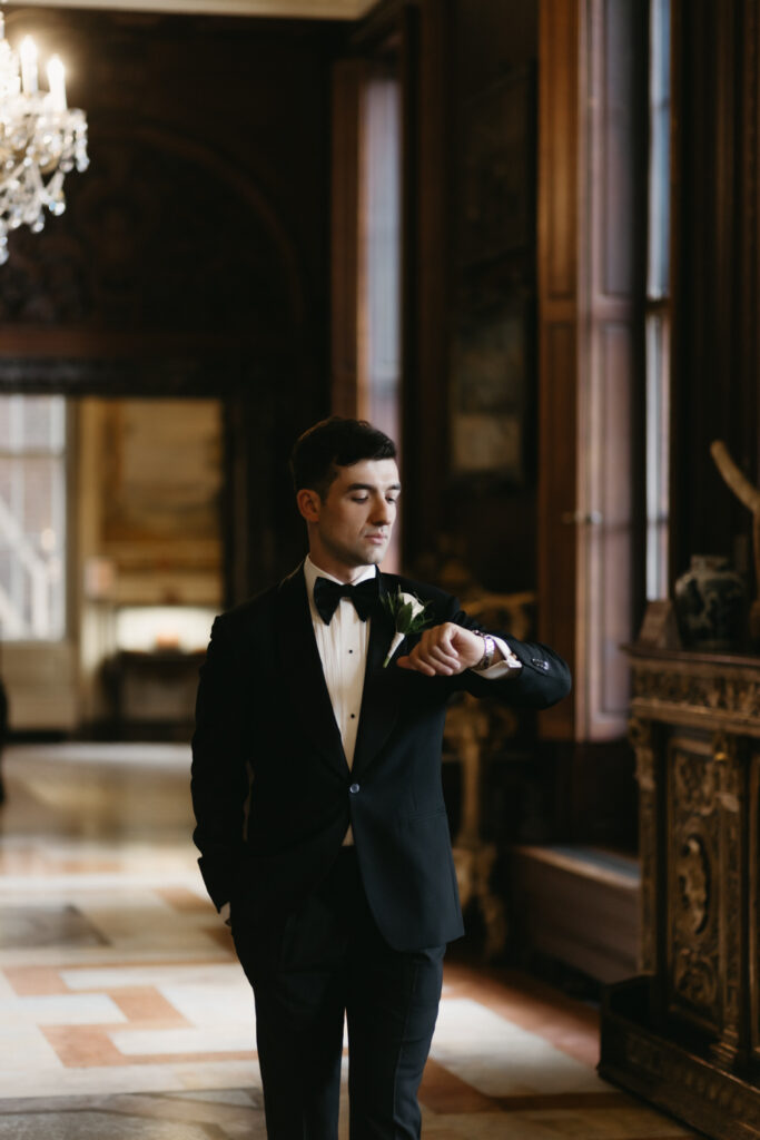 Portrait of groom walking and checking his watch in the Larz Anderson House in Washington DC 