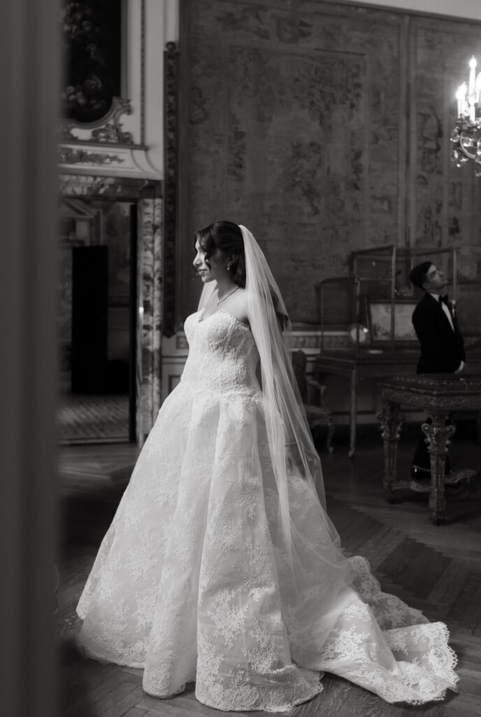 Fine Art Portrait of bride in front of window and the groom standing behind her in the distance at the Larz Anderson House in Washington DC 