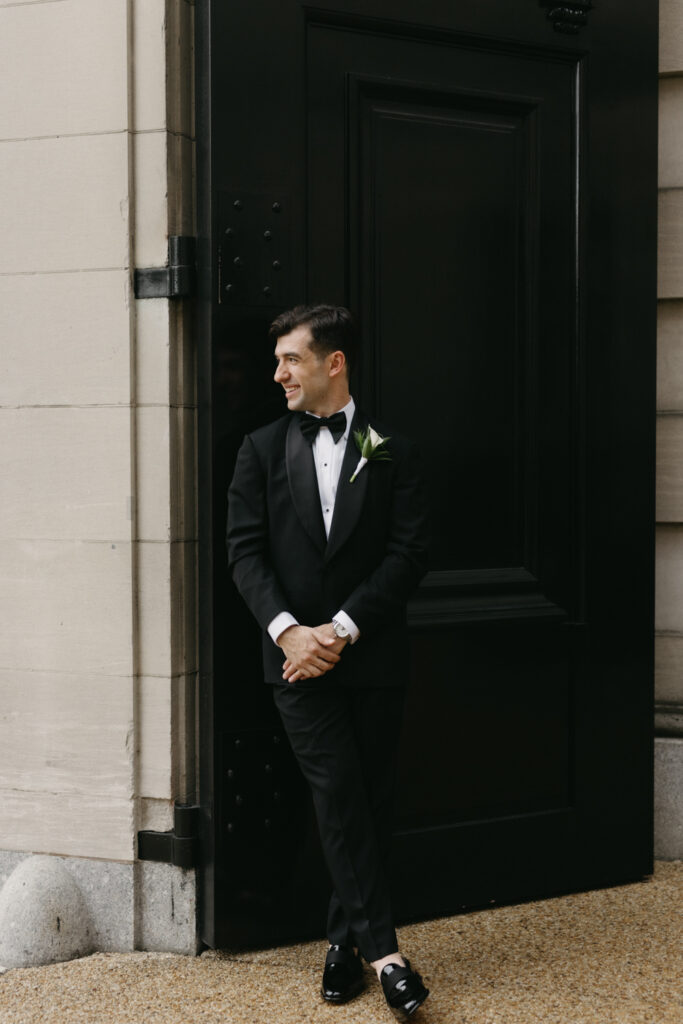 Groom in formal black tie attire posing in front of the Larz Anderson House
