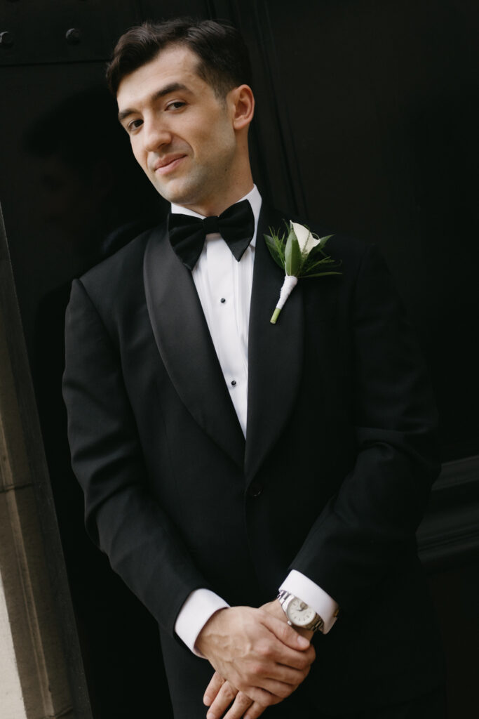Groom in formal black tie attire posing in front of the Larz Anderson House