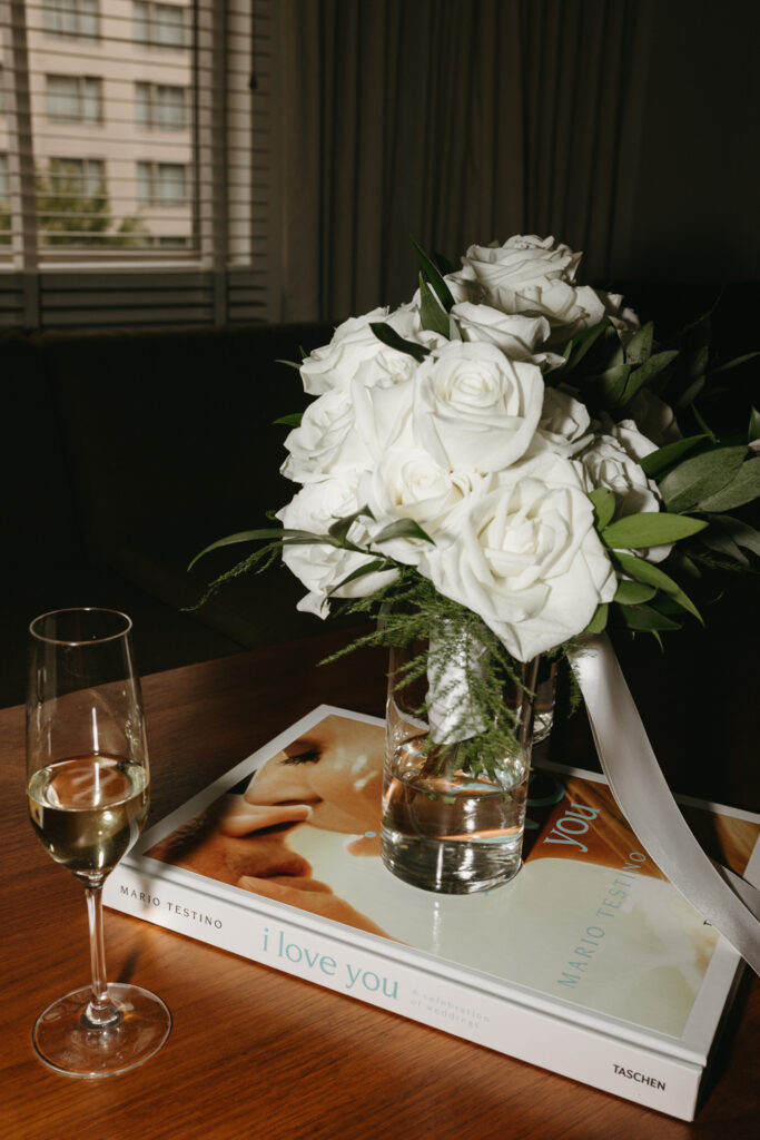 Glass of champagne and a bridesmaid white rose bouquet at the brides getting ready suite at the Hyatt Hotel in Washington DC.