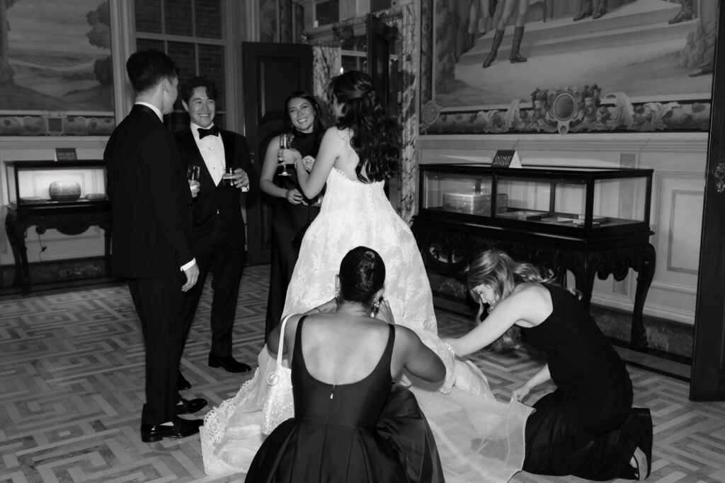 Bride getting her dress bustled by bridesmaids while she talks to her guests at the Larz Anderson House in DC. 