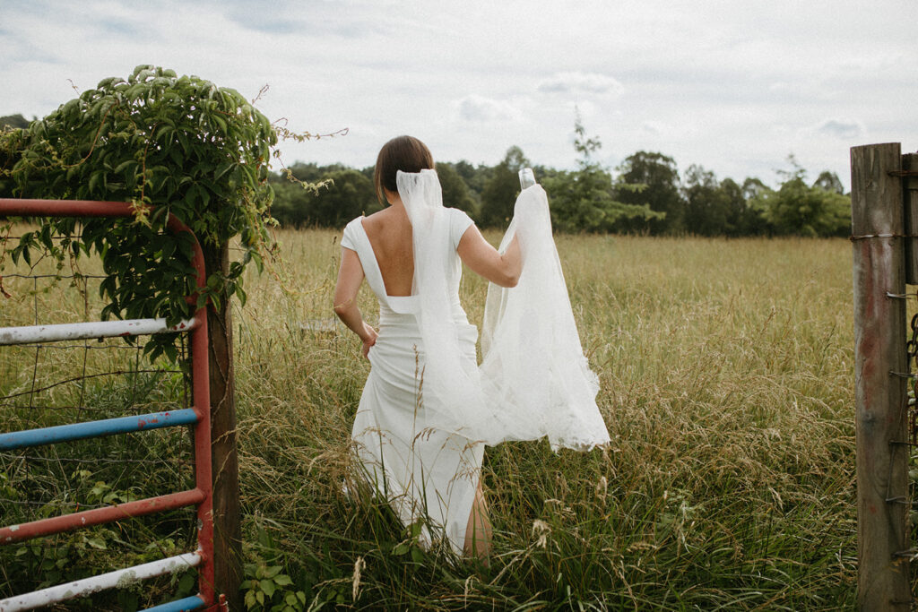 Abingdon Virginia summer wedding — bride and groom embracing in a scenic field with the Blue Ridge Mountains in the distance.