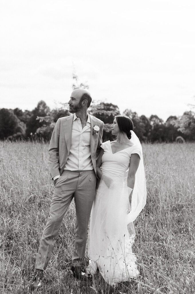 Bride and groom embracing in a scenic field with the Blue Ridge Mountains in the distance.