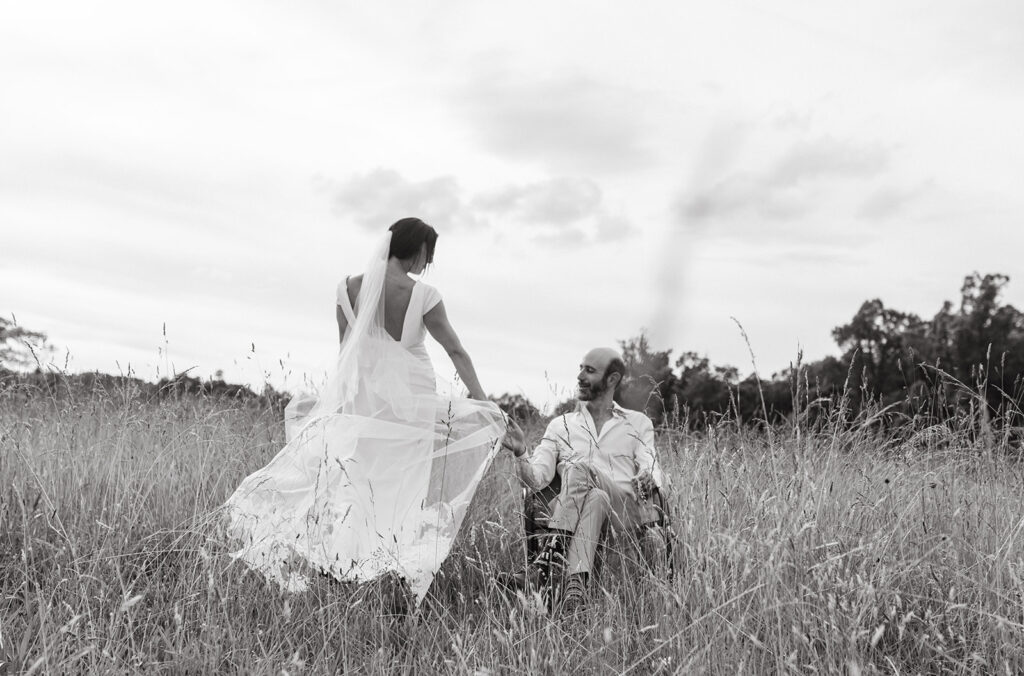 Bride and groom embracing in a scenic field with the Blue Ridge Mountains in the distance.