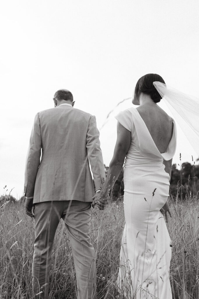 Bride and groom embracing in a scenic field with the Blue Ridge Mountains in the distance.
