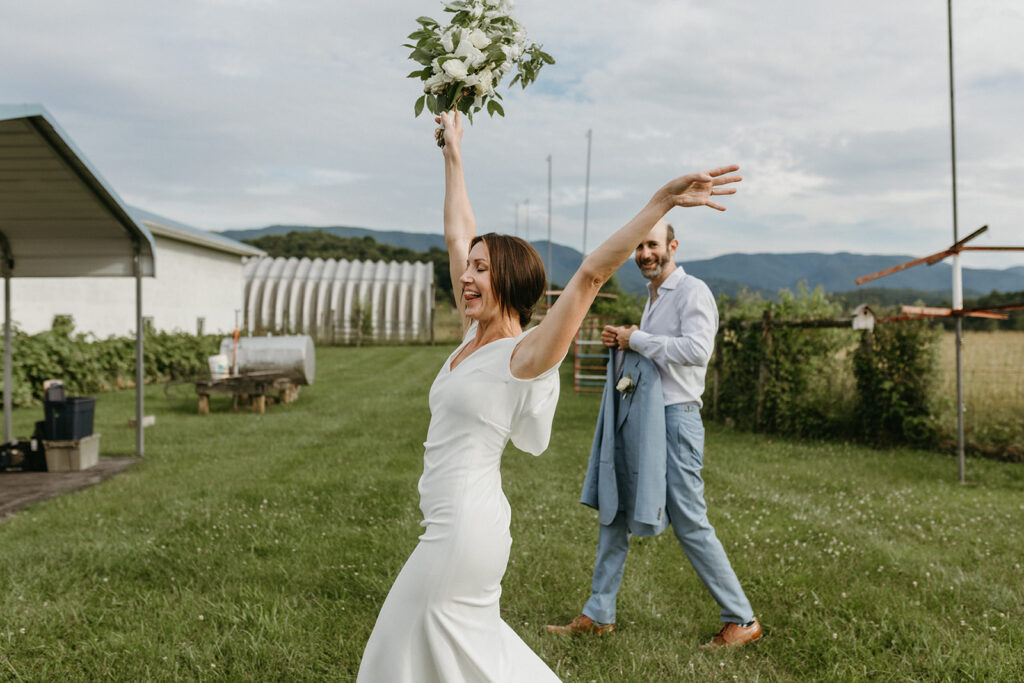 Excited Bride and Groom in a scenic field with the Blue Ridge Mountains in the distance, leaving to go to their cocktail hour.