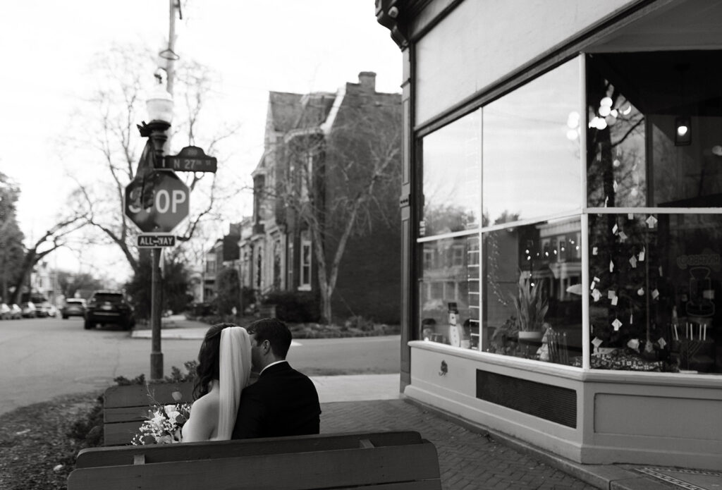 Bride and Groom sitting on bench in front of Riverbend Roastery in the Church Hill neighborhood of Richmond, Virginia.