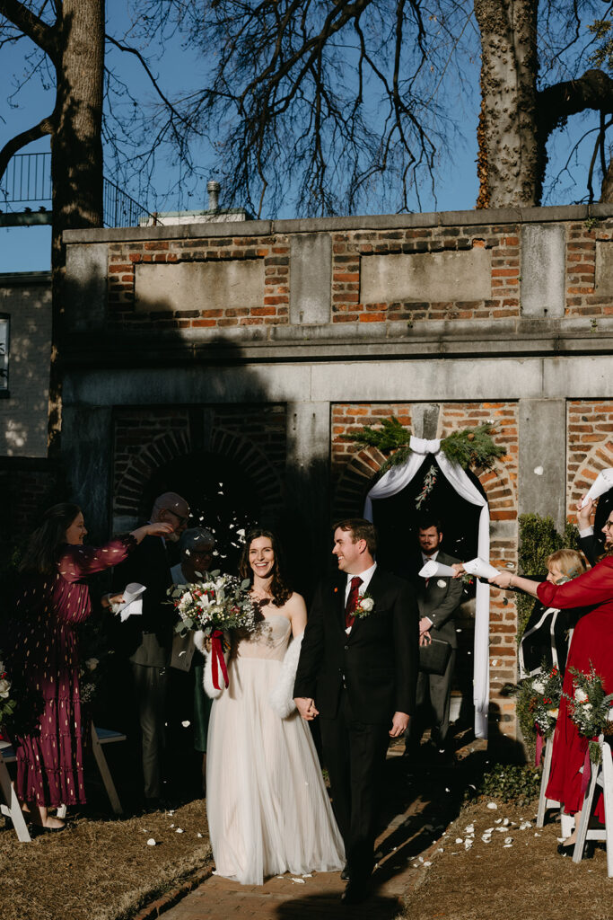 Newlyweds coming up the aisle with guests tossing flower petals at their Richmond winter micro wedding.