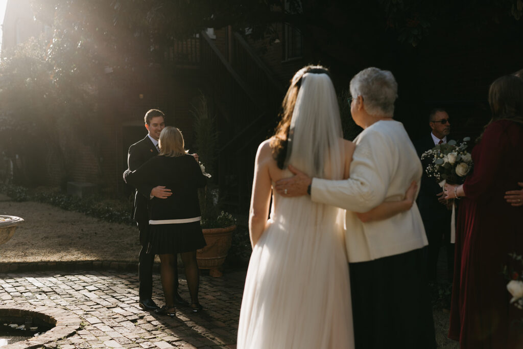 Groom and his mother dancing in the courtyard as family watches. 