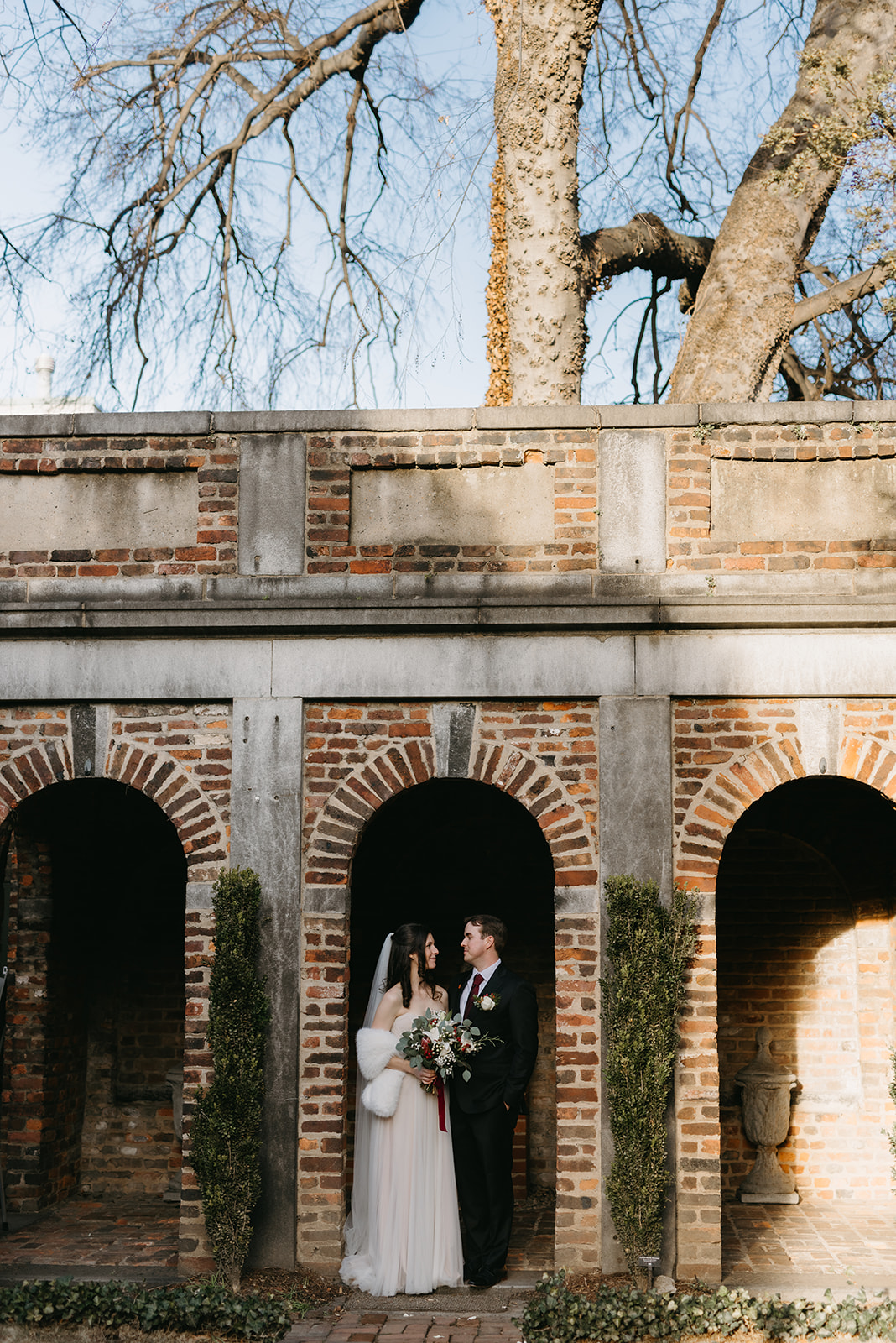 Bride and groom under arch in the courtyard at the Poe Museum in Richmond, Virginia