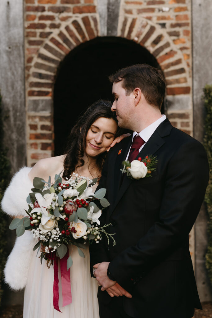 Bride and groom standing under arch in the courtyard of the Poe Museum in Richmond, Virginia.