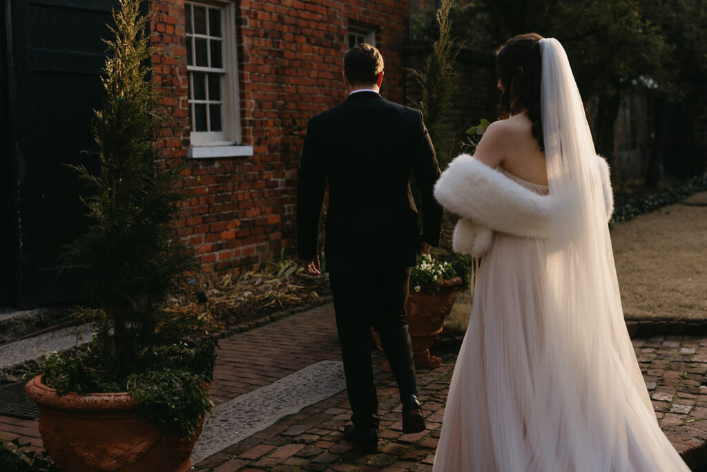 Portrait of bride and groom walking out of the Poe Museum on their wedding day.