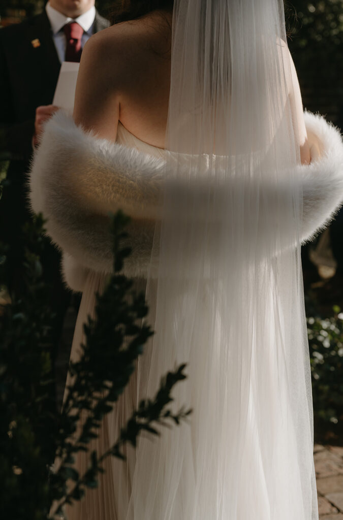 Image of bride standing at the altar with sunlight shining through her veil.