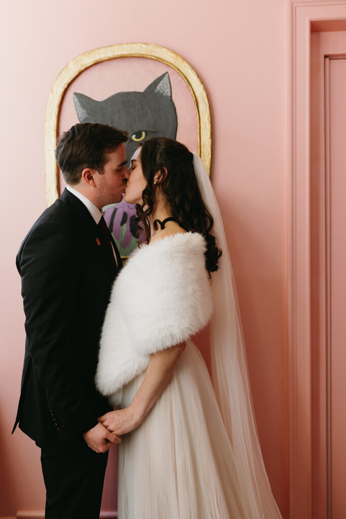 Portrait of Bride and Groom kissing in front of a cat painting in the Quirk Hotel before their Richmond winter micro wedding.