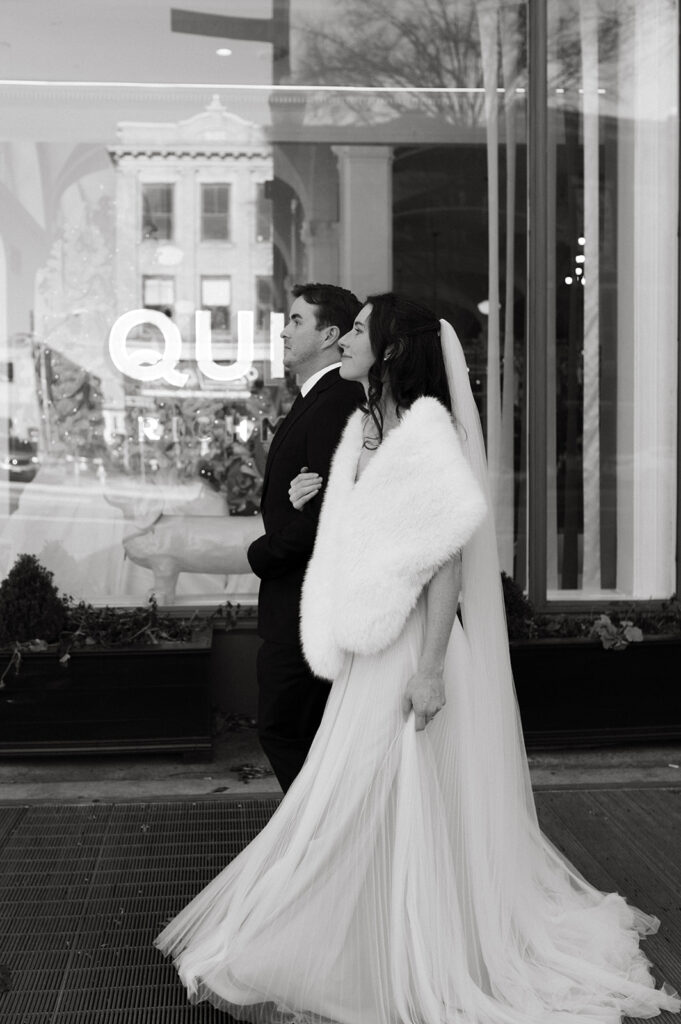 Black and white portrait of a bride and groom exiting Quirk hotel before their Richmond winter micro wedding.