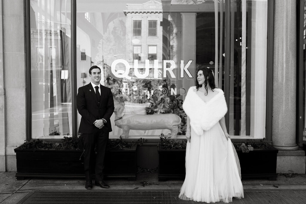 Black and white portrait of a bride and groom standing in front of the Quirk hotel before their Richmond winter micro wedding.