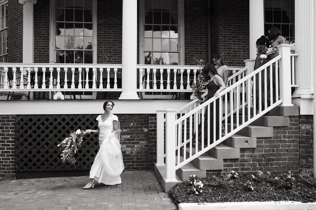 Abingdon Virginia summer wedding — joyful moment of the bride and bridesmaid stepping out of the Martha Washington Inn, capturing casual energy and excitement.